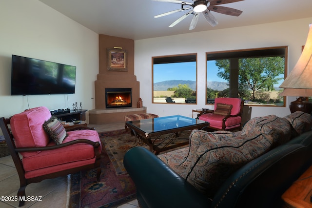 tiled living area with a large fireplace and a ceiling fan