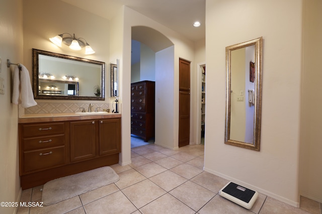 full bath with tile patterned floors, a walk in closet, tasteful backsplash, and vanity