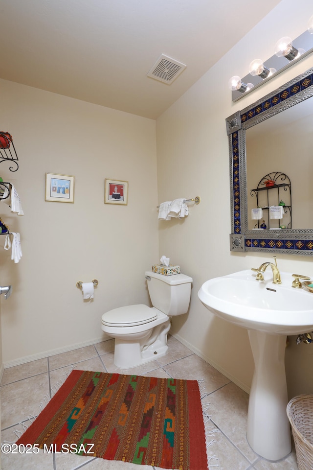 half bathroom with tile patterned flooring, visible vents, baseboards, toilet, and a sink