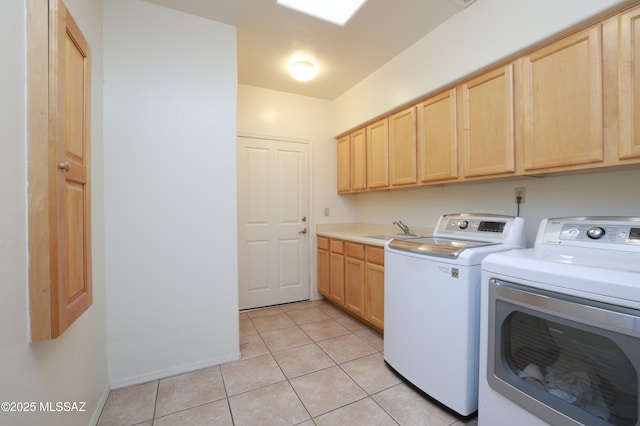 washroom featuring independent washer and dryer, a sink, cabinet space, light tile patterned floors, and baseboards