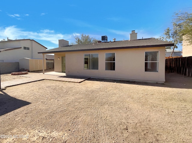 rear view of house featuring central air condition unit, a patio, an outdoor structure, fence private yard, and a chimney