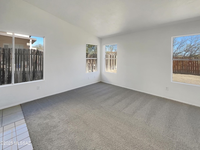 spare room featuring tile patterned floors, baseboards, carpet flooring, and vaulted ceiling