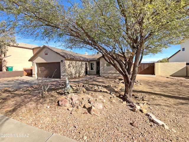 ranch-style house featuring concrete driveway, a gate, an attached garage, and fence