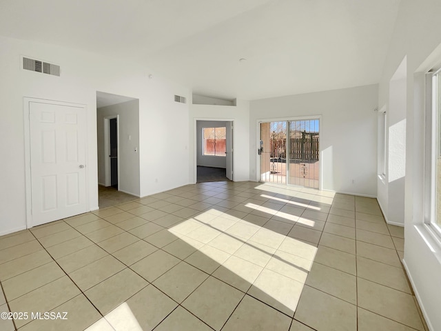 spare room with lofted ceiling, light tile patterned floors, and visible vents