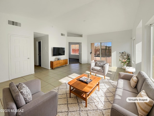 living area with light tile patterned floors, visible vents, and vaulted ceiling