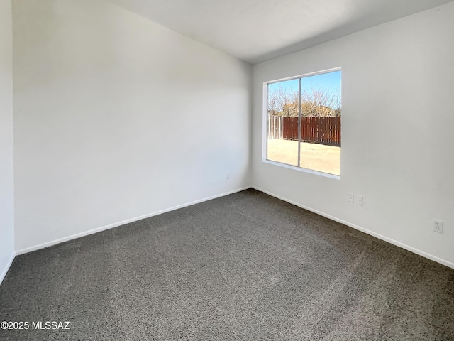 spare room with baseboards and dark carpet