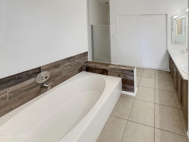 full bathroom with tile patterned flooring, a garden tub, double vanity, a stall shower, and a sink