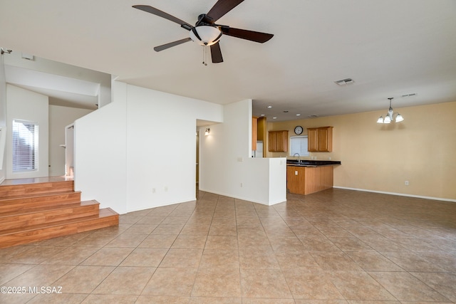 unfurnished living room with visible vents, ceiling fan with notable chandelier, a sink, stairway, and light tile patterned flooring