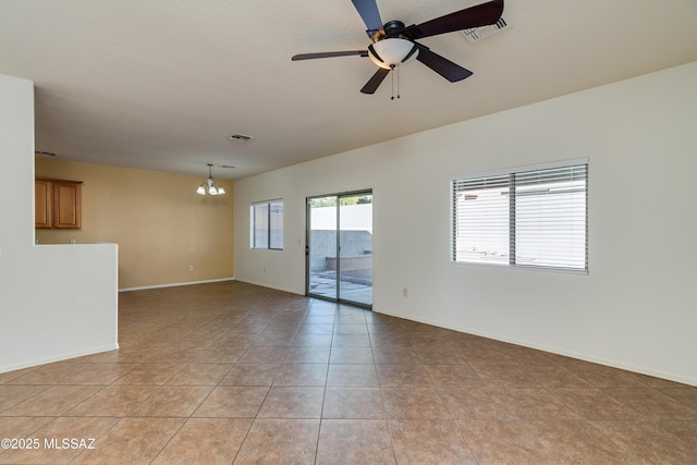 unfurnished room with light tile patterned floors, visible vents, ceiling fan with notable chandelier, and baseboards