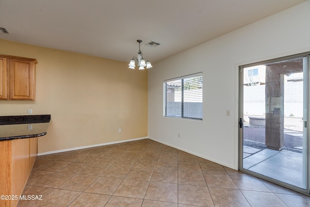 unfurnished dining area with light tile patterned floors, a notable chandelier, baseboards, and visible vents