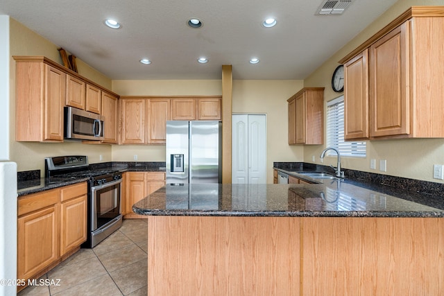 kitchen with visible vents, light tile patterned floors, a peninsula, stainless steel appliances, and a sink