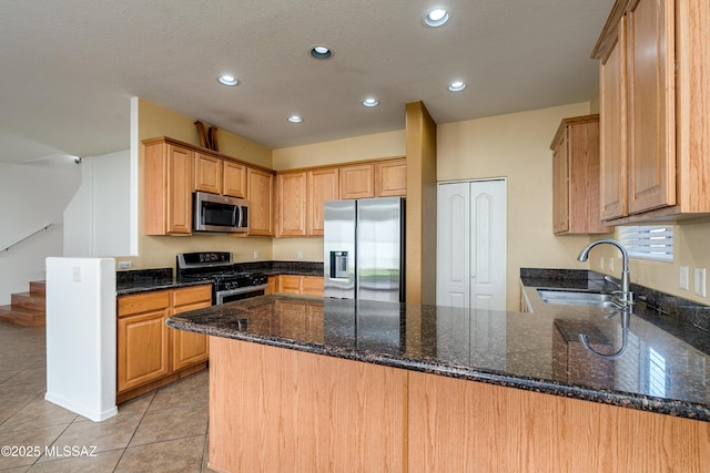 kitchen with light tile patterned flooring, appliances with stainless steel finishes, a peninsula, and a sink