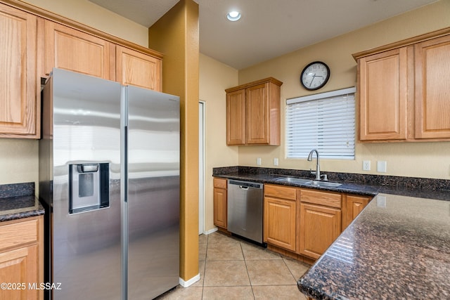 kitchen featuring a sink, dark stone countertops, recessed lighting, stainless steel appliances, and light tile patterned floors