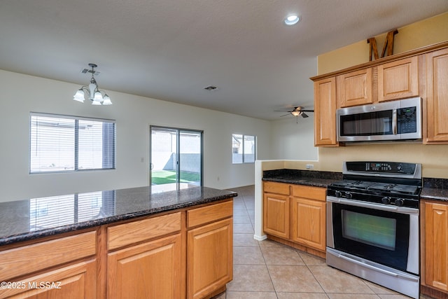 kitchen featuring visible vents, dark stone counters, light tile patterned flooring, appliances with stainless steel finishes, and ceiling fan with notable chandelier