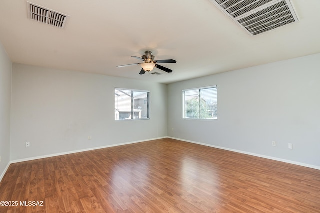 empty room featuring visible vents, a healthy amount of sunlight, and wood finished floors