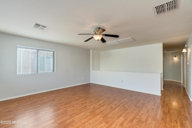 empty room with a ceiling fan, light wood-style floors, and visible vents