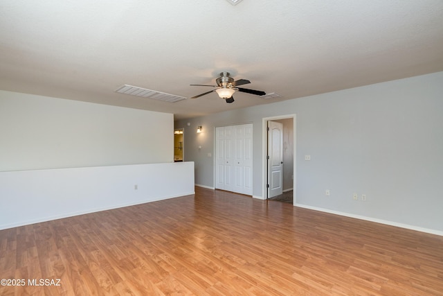 spare room featuring visible vents, a ceiling fan, light wood-type flooring, and baseboards