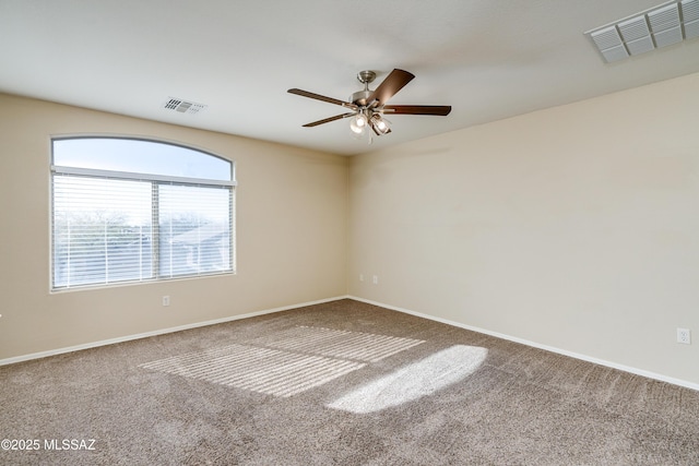 spare room featuring carpet, a ceiling fan, visible vents, and baseboards