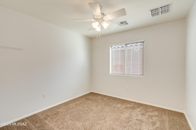 carpeted spare room featuring baseboards, visible vents, and ceiling fan