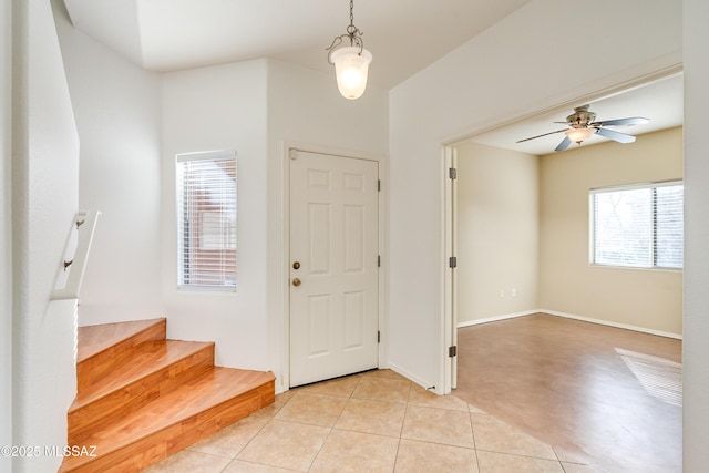 entrance foyer with light tile patterned flooring, baseboards, stairs, and a ceiling fan