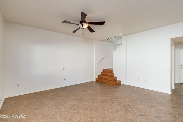 unfurnished room with visible vents, light tile patterned floors, baseboards, ceiling fan, and stairs