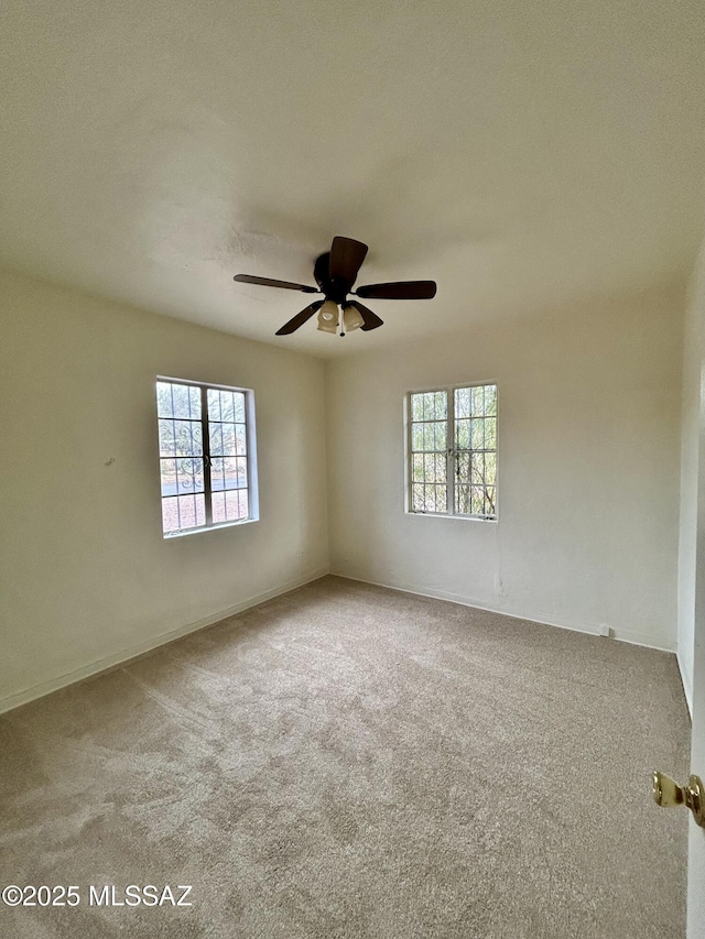 carpeted spare room with a ceiling fan