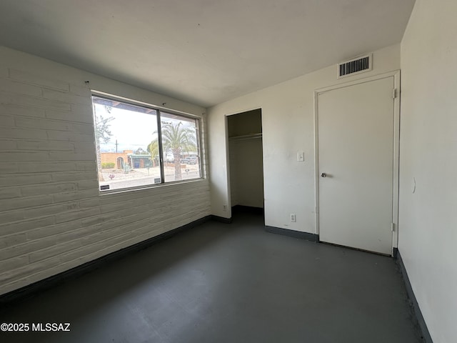 unfurnished bedroom featuring visible vents, baseboards, a closet, and finished concrete flooring