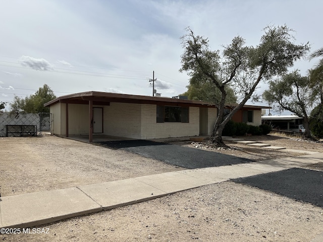 single story home with brick siding, driveway, and fence