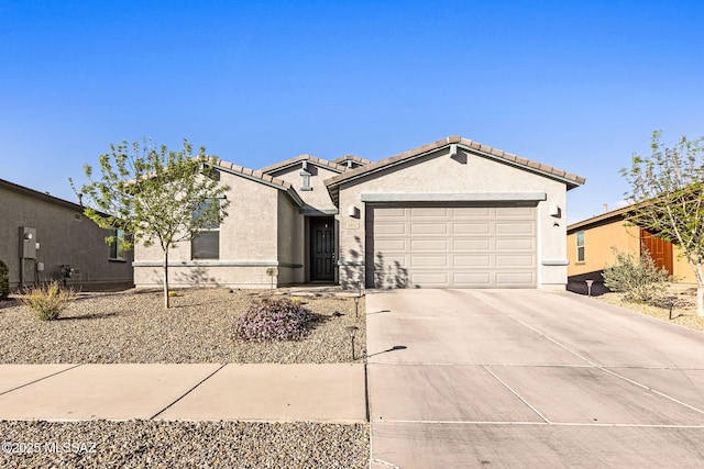 ranch-style house featuring a tile roof, stucco siding, an attached garage, and concrete driveway