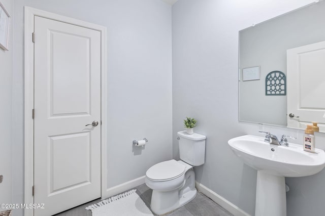 half bath with baseboards and toilet