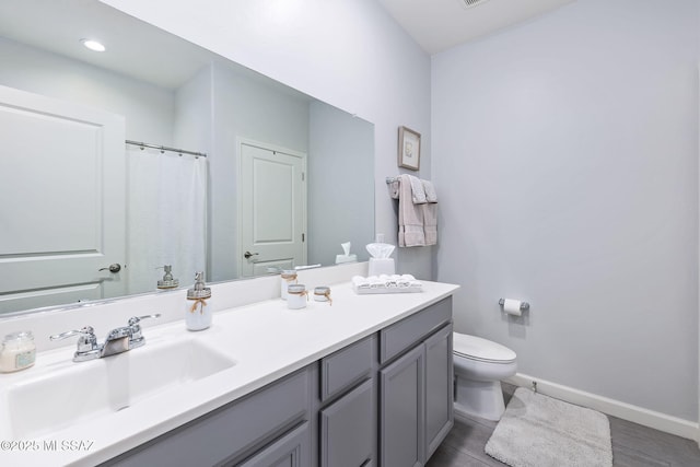 full bathroom featuring baseboards, toilet, and vanity