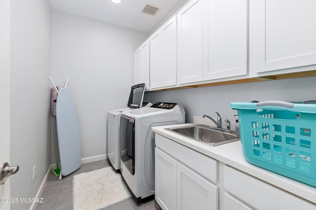 laundry room featuring visible vents, a sink, cabinet space, separate washer and dryer, and baseboards