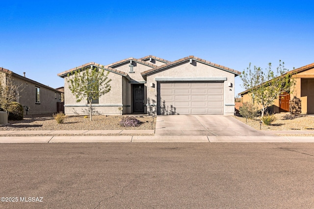 view of front of house featuring concrete driveway, a tiled roof, an attached garage, and stucco siding