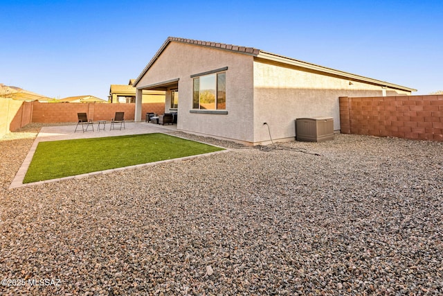 rear view of property with stucco siding, a patio, a yard, and a fenced backyard