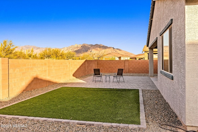 view of yard featuring a mountain view, a fenced backyard, and a patio area