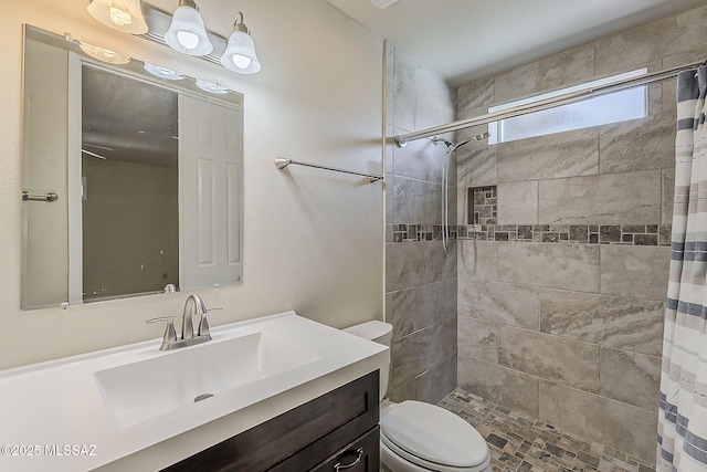 full bath with toilet, vanity, and a tile shower
