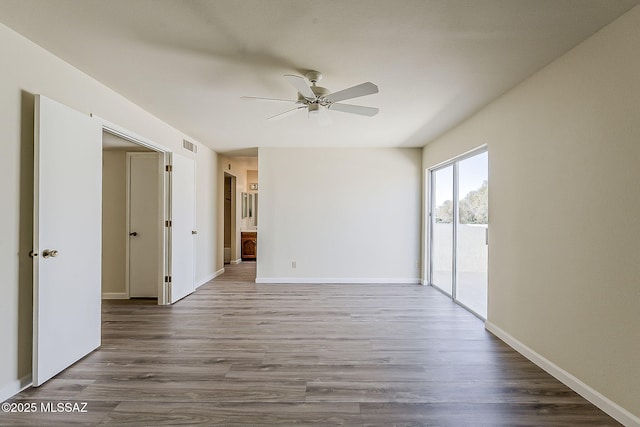 empty room with baseboards, visible vents, wood finished floors, and a ceiling fan