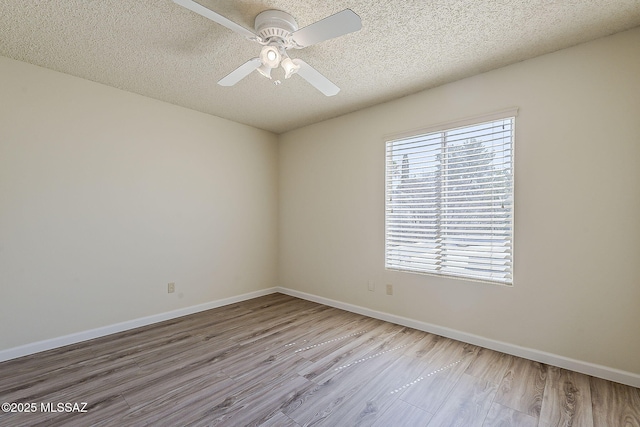 spare room featuring a textured ceiling, baseboards, and wood finished floors