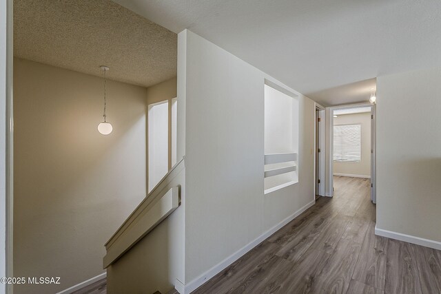 hall featuring baseboards, a textured ceiling, and dark wood-style floors