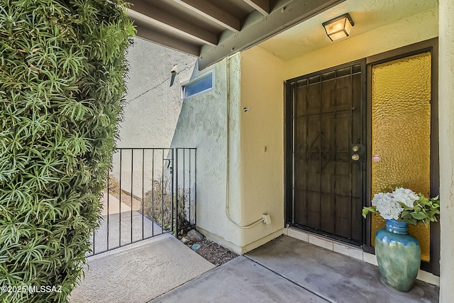 property entrance featuring a gate and stucco siding