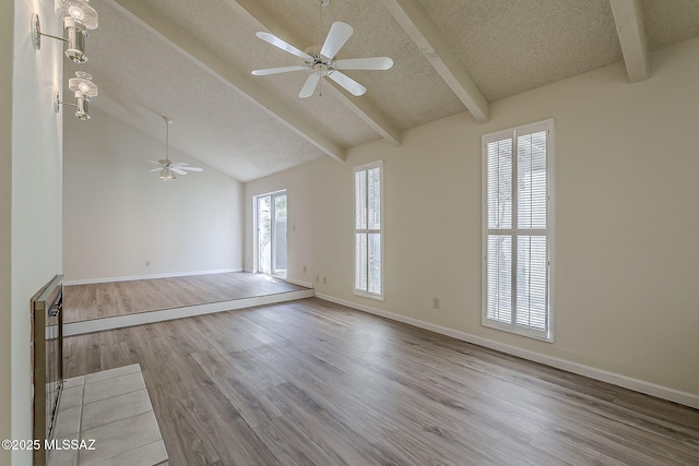 unfurnished room with a textured ceiling, baseboards, wood finished floors, a ceiling fan, and vaulted ceiling with beams