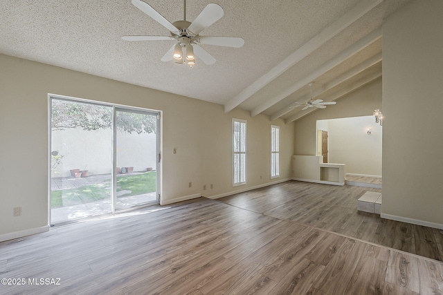unfurnished living room with lofted ceiling with beams, baseboards, a textured ceiling, a ceiling fan, and wood finished floors