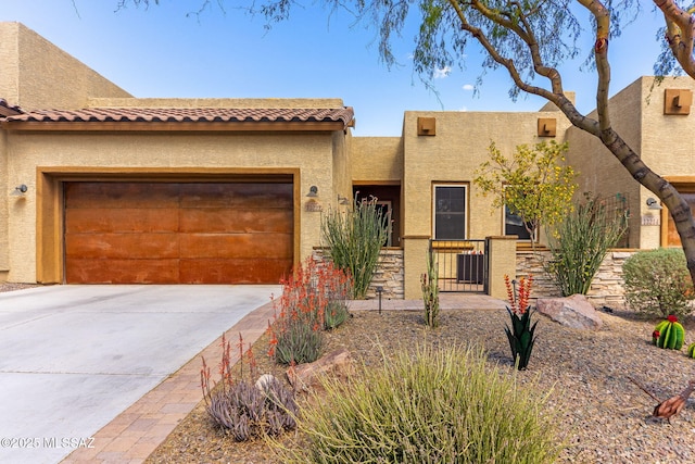 adobe home with stucco siding, driveway, an attached garage, and a tiled roof