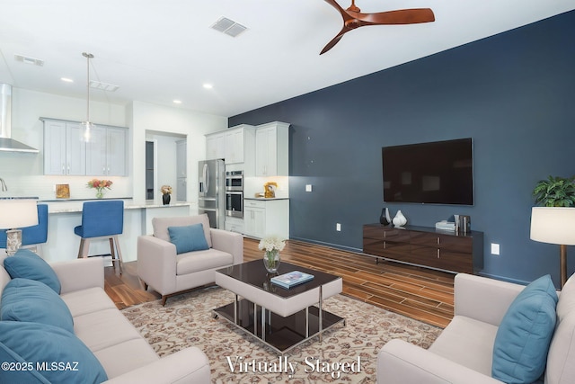 living room with visible vents, a ceiling fan, and light wood finished floors