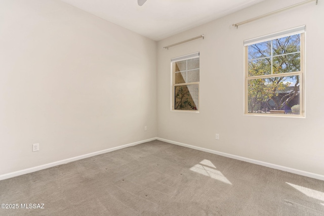 carpeted spare room featuring baseboards and ceiling fan