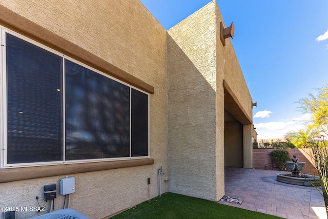 view of side of home featuring a patio area, stucco siding, and fence