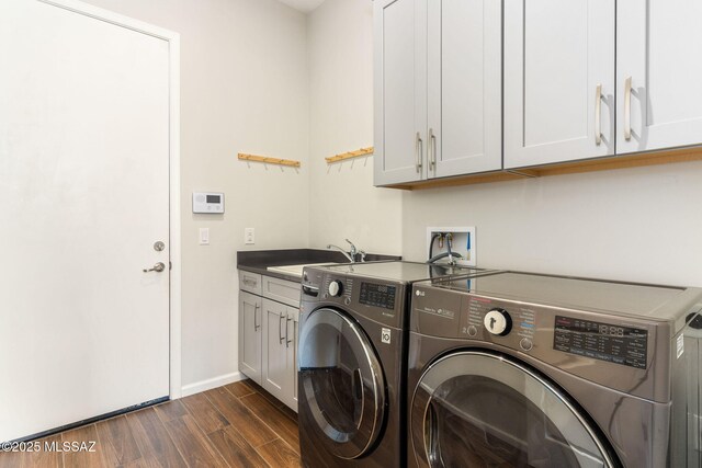 laundry area with cabinet space, a sink, baseboards, dark wood-type flooring, and washer and clothes dryer