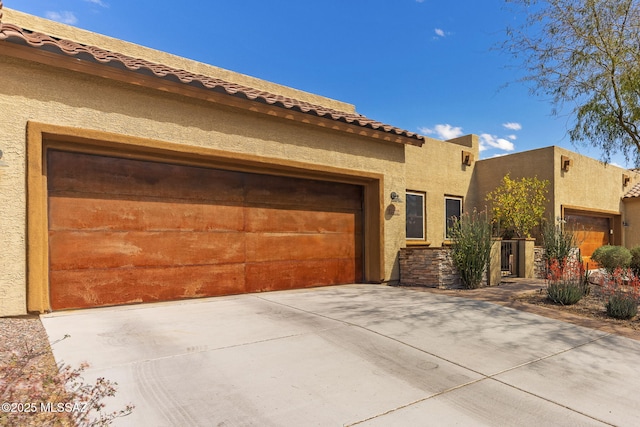 view of front facade featuring a garage, stucco siding, driveway, and a tile roof