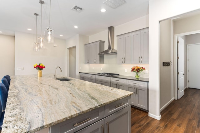 kitchen with visible vents, a sink, gray cabinetry, dark wood-type flooring, and wall chimney range hood