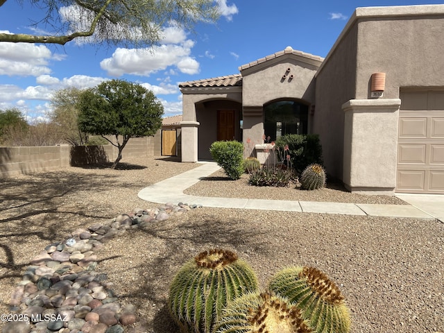 exterior space with stucco siding, a tiled roof, an attached garage, and fence